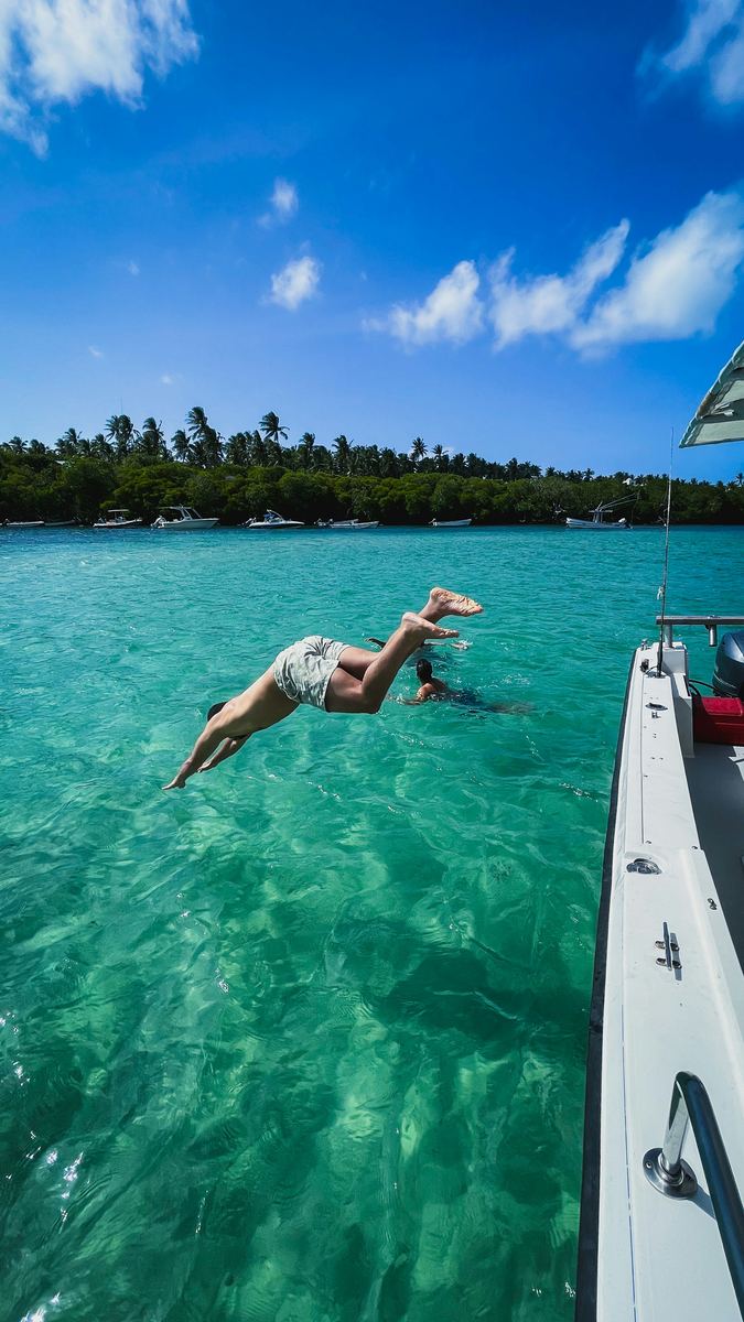 Woman diving off a boat into clear turquoise water