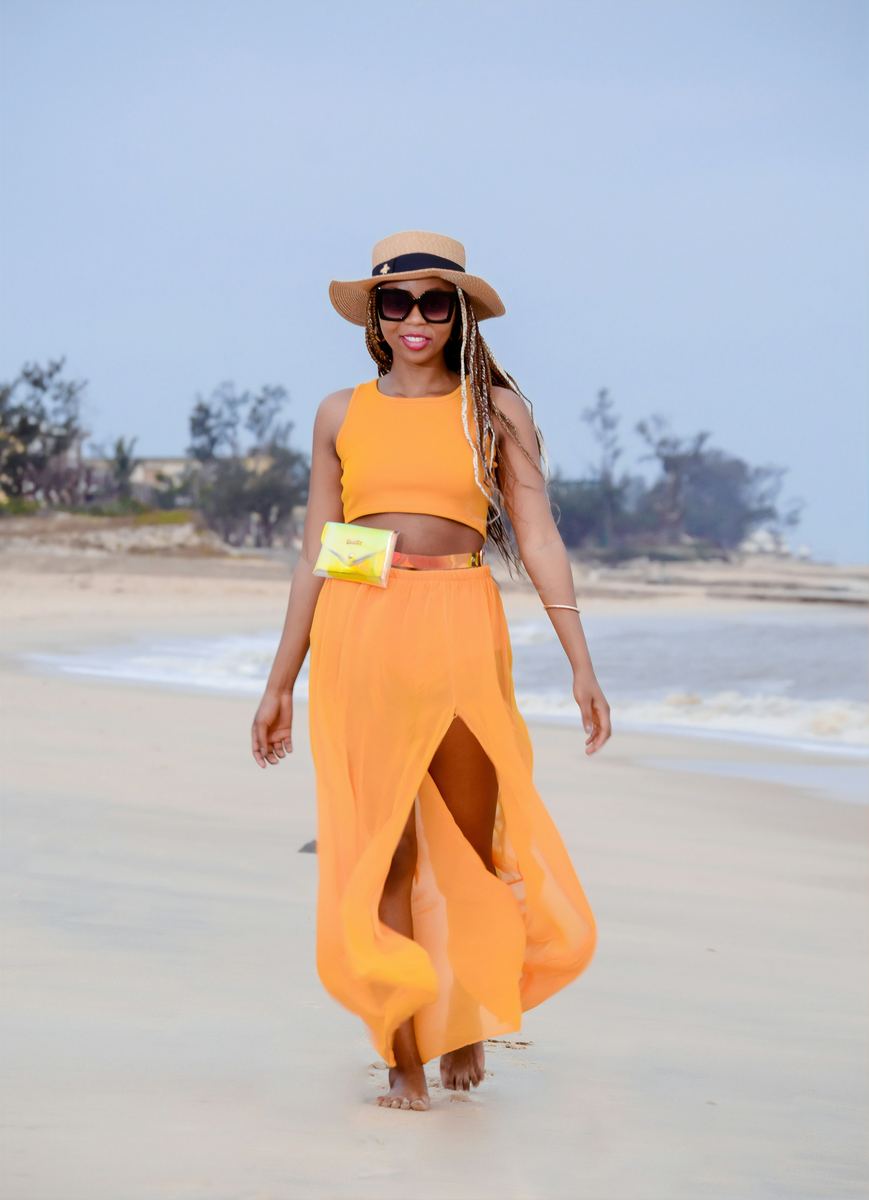 Woman in an orange sarong skirt and matching top walking on the beach
