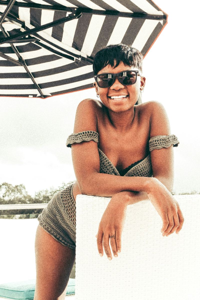 Woman in a striped off-shoulder bikini top under a beach umbrella