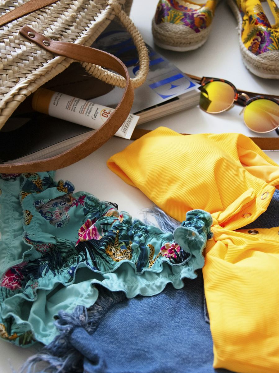 A beach bag packed with swimwear, sunglasses and sandals