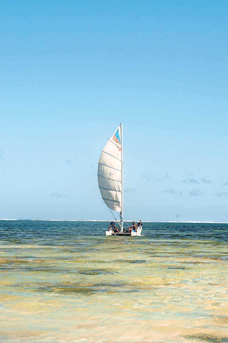 A traditional sailing boat off a Kenyan beach in shallow turquoise water